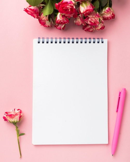 Mise à plat du bureau avec bouquet de roses et carnet