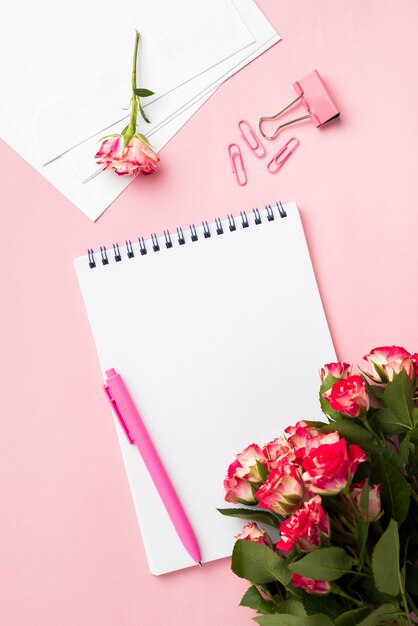 Mise à plat du bureau avec carnet et bouquet de roses