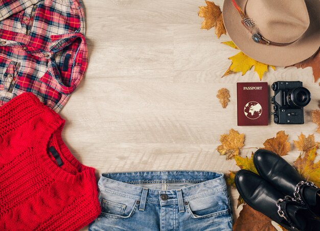 Mise à plat du style femme et accessoires, pull en tricot rouge, chemise à carreaux, jeans en denim, bottes en cuir noir, chapeau, tendance de la mode automne, vue d'en haut, appareil photo vintage, passeport