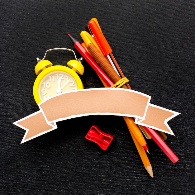 Mise à plat des éléments essentiels de l'école avec horloge et crayons