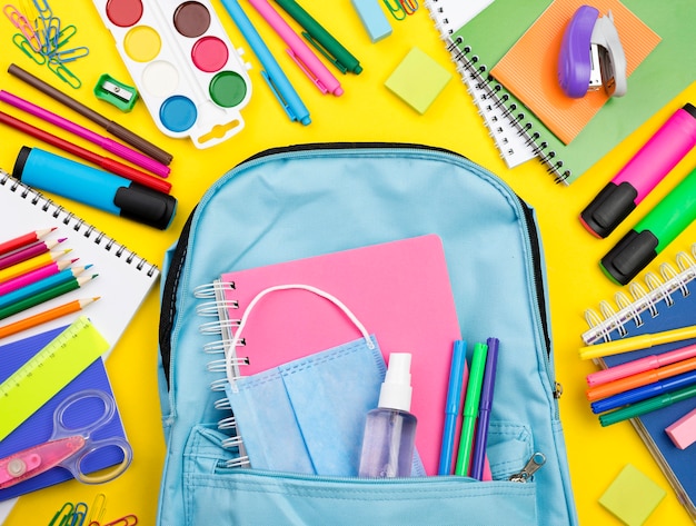 Mise à plat des essentiels de l'école avec des crayons multicolores et un sac à dos