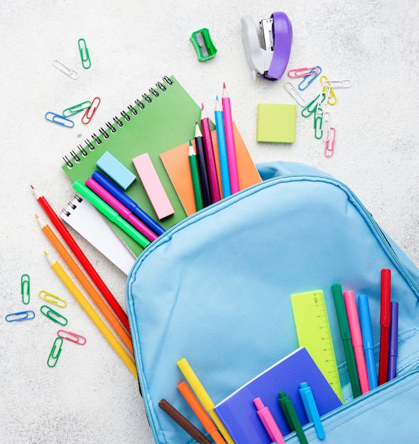 Photo gratuite mise à plat des essentiels de l'école avec des crayons et un sac à dos