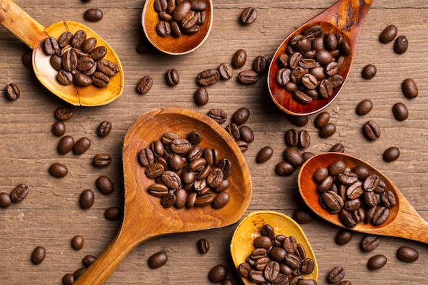 Photo gratuite mise à plat des grains de café dans des cuillères en bois