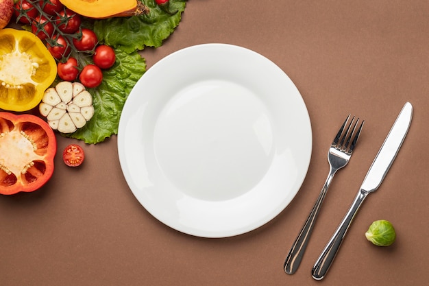 Mise à plat de légumes biologiques avec assiette et couverts