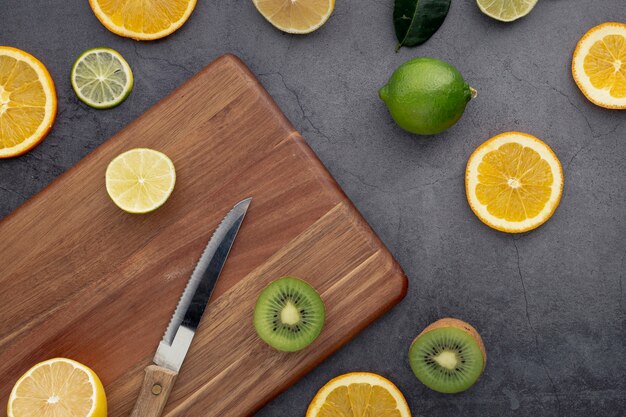 Mise à plat de mandarines et de tranches de kiwi avec planche à découper et couteau