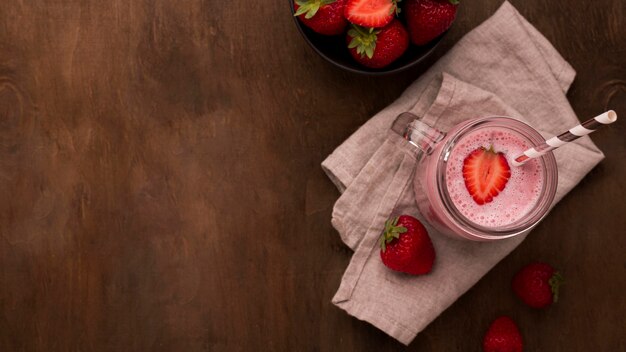 Mise à plat de milkshake aux fraises avec paille et espace copie