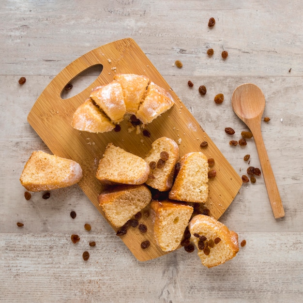 Photo gratuite mise à plat de morceaux de beignets sur une planche à découper avec des raisins secs