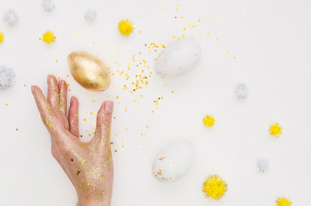 Mise à plat d'oeuf d'or pour Pâques avec des paillettes et des pissenlits