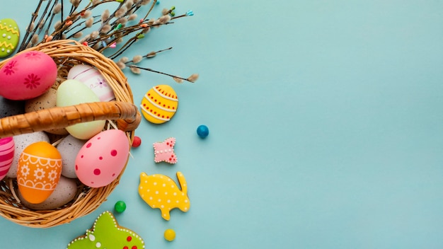 Mise à plat d'oeufs de Pâques dans le panier avec des formes de lapin et de papillon