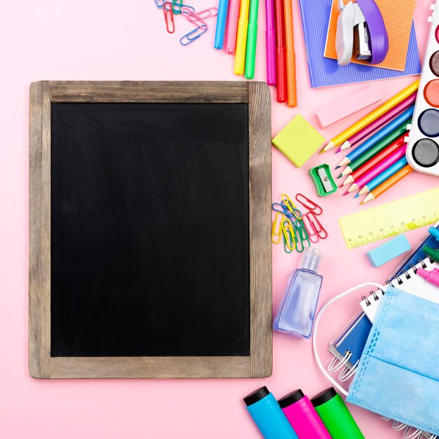 Mise à plat de la papeterie de retour à l'école avec tableau noir et masque médical