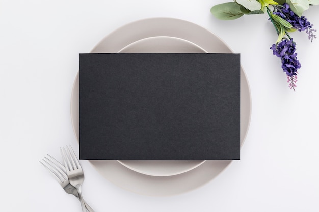 Mise à plat de papier de menu vierge sur des assiettes avec des fourchettes et des fleurs