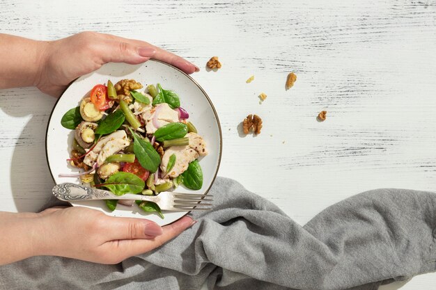 Mise à plat d'une personne tenant une assiette avec des aliments diététiques céto