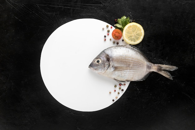 Photo gratuite mise à plat de poisson avec assiette et citron