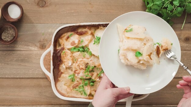Mise à plat. pommes de terre festonnées fraîchement sorties du four garnies de persil dans un plat de cuisson en céramique blanche.