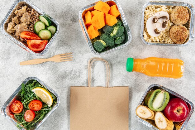 Mise à plat de sac en papier avec des repas dans des casseroles et du jus d'orange