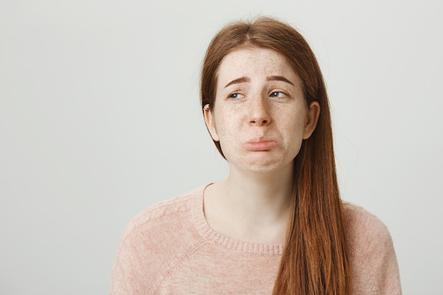 Misérable jolie fille rousse faisant la moue et grimaçant, semble jalouse