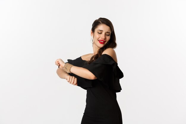 Mode et beauté. femme se sentant heureuse et dansant en robe de soirée noire, debout insouciant sur fond blanc.
