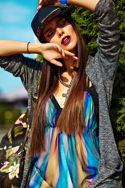Mode élégante belle jeune femme brune modèle en été hipster vêtements décontractés colorés posant sur la rue