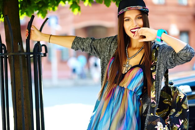 Mode élégante belle jeune femme brune modèle en été hipster vêtements décontractés colorés posant sur la rue