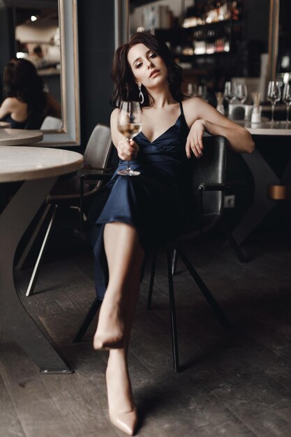 mode jolie femme en robe au restaurant avec du vin