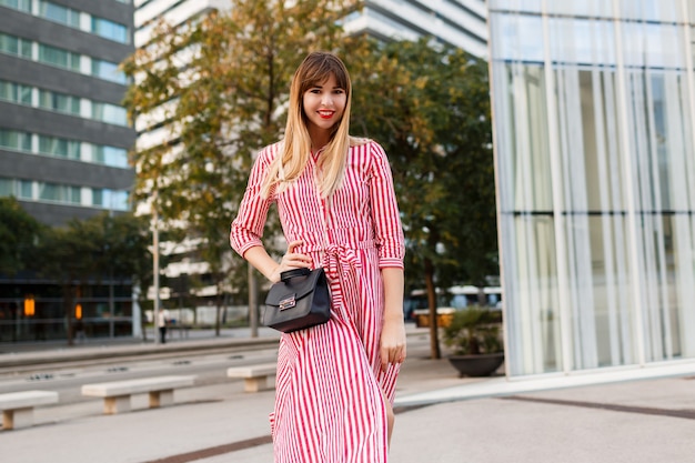 Mode jolie femme en robe rouge posant dans la rue.