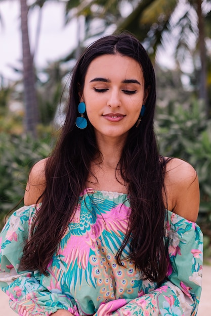 Photo gratuite mode portrait de femme élégante en haut à manches longues imprimé coloré et short rose sur la plage, fond tropical.