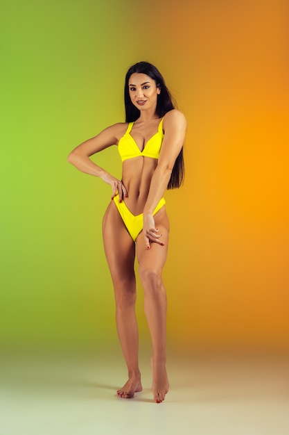 Mode portrait de jeune femme fit et sportive en maillot de bain de luxe jaune élégant sur gradient. Corps parfait prêt pour l'été.