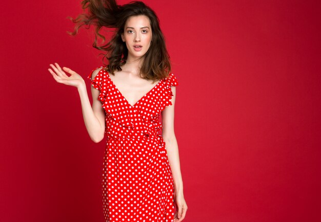 Mode portrait de jeune femme souriante en robe à pois rouge sur rouge