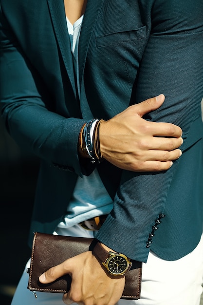 Mode portrait de jeune homme d'affaires beau modèle homme en costume de tissu décontracté avec accessoires sur les mains