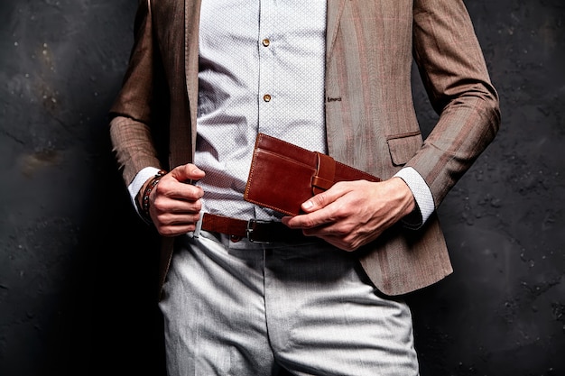 Mode portrait de jeune homme d'affaires beau modèle homme habillé en élégant costume marron avec accessoires