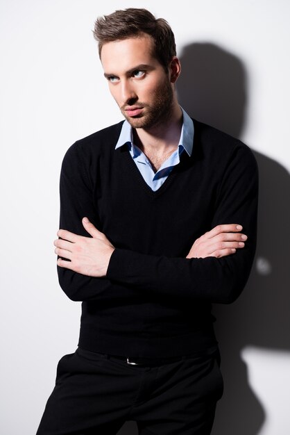 Mode portrait de jeune homme en pull noir et chemise bleue avec les bras croisés