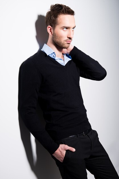 Mode portrait de jeune homme en pull noir et chemise bleue avec des ombres contrastées