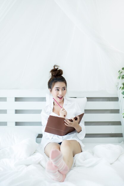 Mode de vie heureux jeune femme asiatique jouissant couché sur le livre de lecture à la maison.