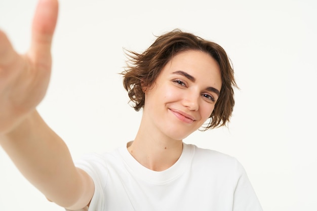 Photo gratuite mode de vie et personnes jeune femme souriante et prenant un selfie posant pour une photo tenant un appareil photo avec un