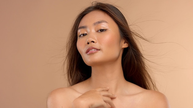 Modèle asiatique de beauté sensuelle sur fond beige Maquillage naturel peau brillante humide