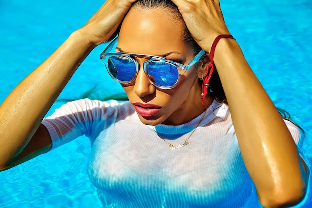 modèle aux cheveux noirs en maillot de bain blanc sortant de la piscine