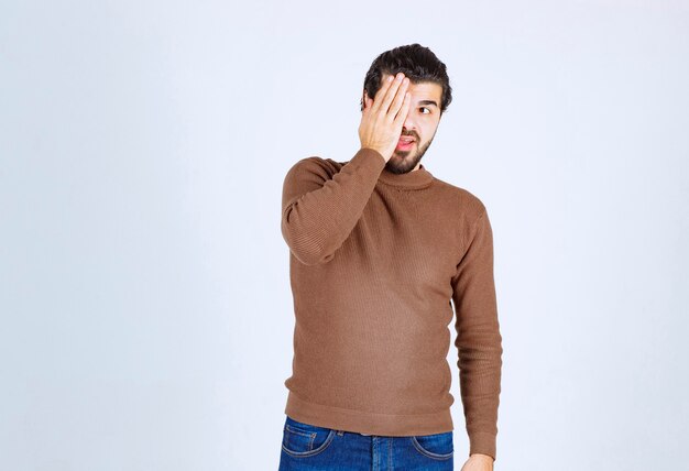 modèle de beau jeune homme couvrant les yeux avec la main.