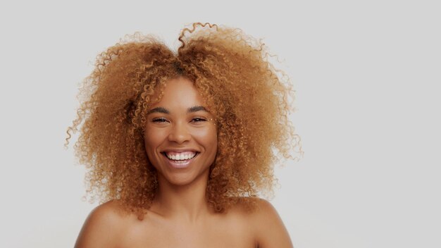 Modèle blond noir de race mixte aux cheveux bouclés souriant heureux de le toucher