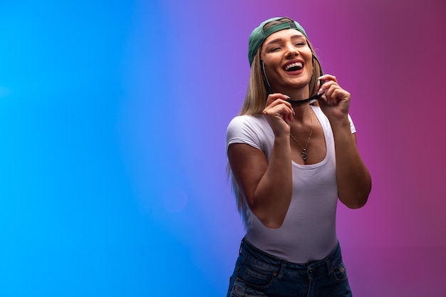 Modèle blond portant une casquette verte et des lunettes de soleil en moulages et s'amusant.