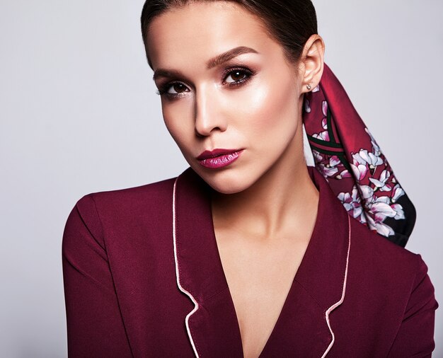 modèle brune en costume rouge avec maquillage de soirée sur gris