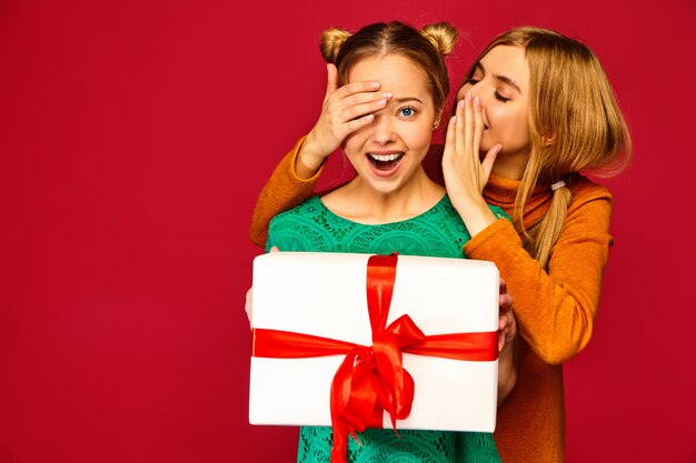 Modèle couvrant les yeux de son amie et lui donnant un grand coffret cadeau et un secret haring