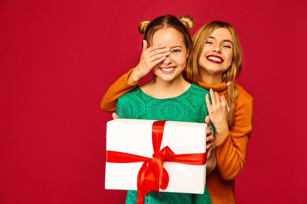 Modèle couvrant les yeux de son amie et lui donnant un grand coffret cadeau