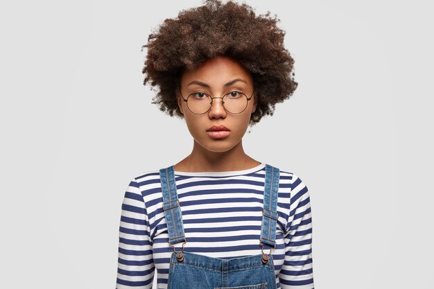 Modèle féminin afro-américain sérieux regarde avec confiance la caméra