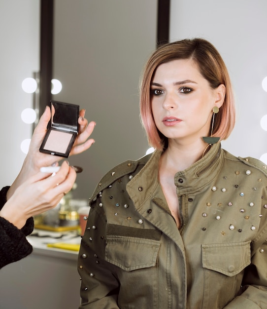 Modèle féminin assis en studio de maquillage