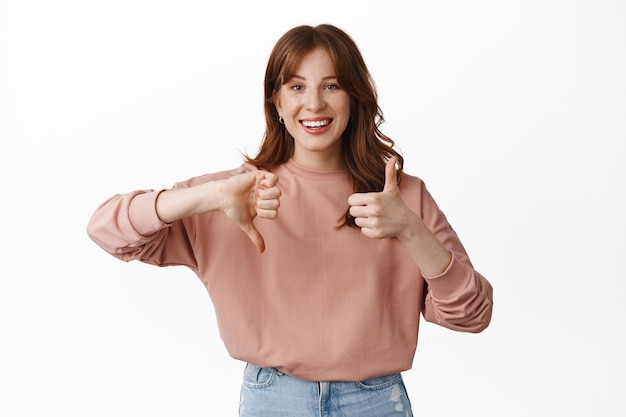 Modèle féminin rousse souriante, montrant le pouce vers le haut, taux moyen moyen, laisser des commentaires, debout sur blanc