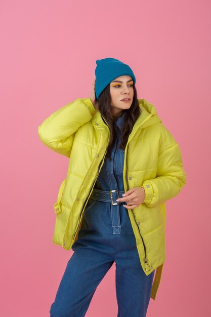 Modèle de femme active attrayante posant sur un mur rose en veste d'hiver colorée de couleur jaune vif, tendance de la mode manteau chaud