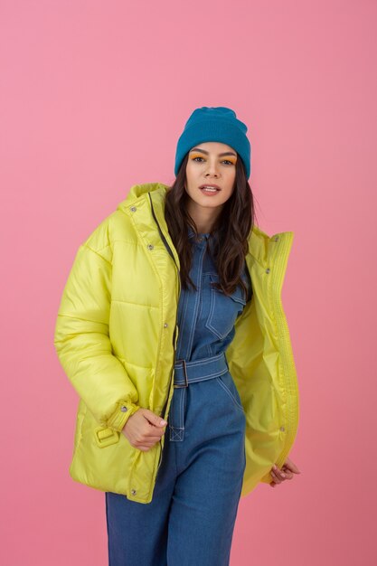 Modèle de femme active attrayante posant sur un mur rose en veste d'hiver colorée de couleur jaune vif, tendance de la mode manteau chaud