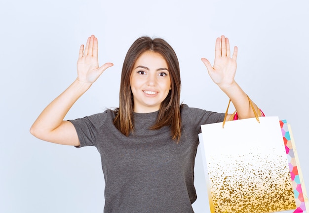 Un modèle de femme heureuse tenant beaucoup de sacs à provisions sur fond blanc.