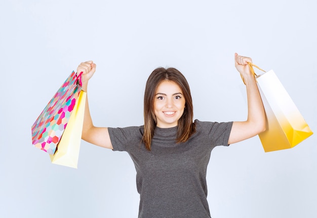 Un modèle de femme heureuse tenant beaucoup de sacs à provisions sur fond blanc.