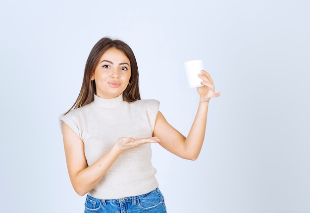 Un modèle de femme souriante montrant un gobelet en plastique et posant.